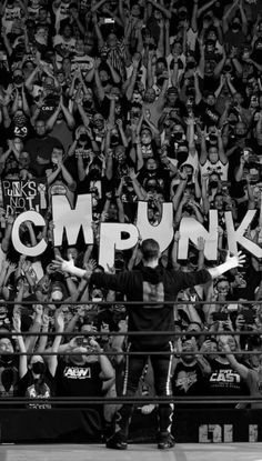 a man standing on top of a wrestling ring in front of a crowd with his arms up