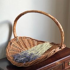 a wicker basket sitting on top of a wooden table next to a drawer with dried lavenders in it