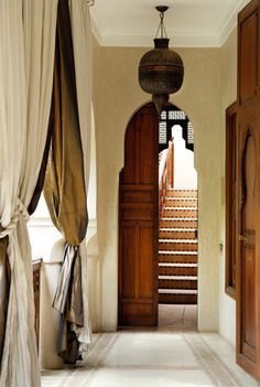 an open door leading to a hallway with curtains on either side and stairs in the middle