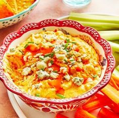 a red and white bowl filled with food on top of a plate next to carrots