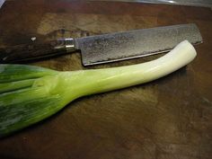 a knife and some green onions on a cutting board