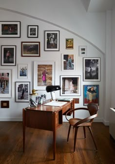 a dining room table and chairs in front of a wall with pictures on the walls