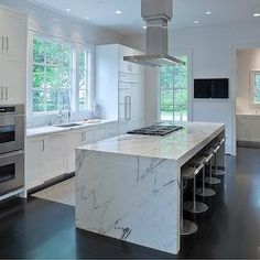 a large kitchen with marble counter tops and stainless steel stove top ovens in it