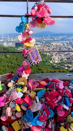 many colorful padlocks are attached to a metal pole with city in the background