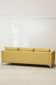 a yellow couch sitting on top of a cement floor next to a white wall in an empty room