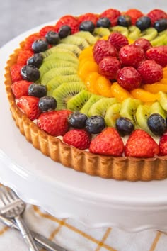 a fruit tart on a white plate with silverware