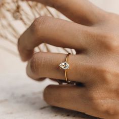 a woman's hand wearing a gold ring with a small diamond on the side