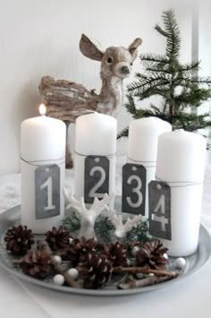 some candles are sitting on a plate with pine cones