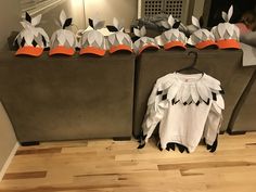 a group of paper birds sitting on top of a wooden floor next to a couch