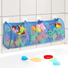 three bins filled with different colored buttons on the side of a bathtub next to a white tiled wall