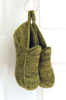 two green mittens hanging from a hook on a door