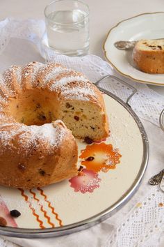 a bundt cake on a plate next to a glass of water