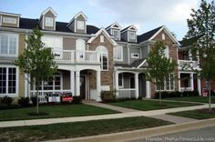 a row of townhouses with trees and grass in front