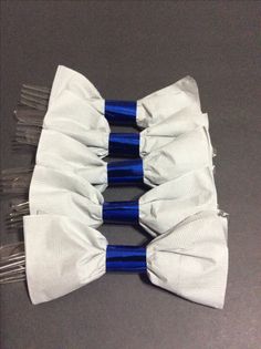 four white and blue bows on top of each other with silver pins in the middle