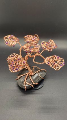 a wire tree sculpture sitting on top of a rock