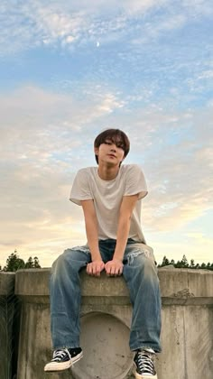 a young man sitting on top of a cement wall next to a white toilet bowl