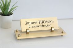 a wooden sign sitting on top of a white table next to a potted plant