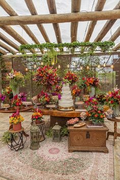 a wedding cake surrounded by potted flowers and greenery on an outdoor patio area