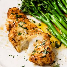 a white plate topped with chicken and asparagus next to broccoli spears