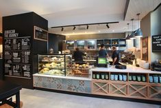 the inside of a coffee shop with menus on the wall and people working behind the counter