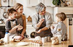 an older woman and two young children standing in front of a kitchen counter with ingredients on it