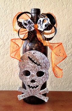 a bottle that has some decorations on it and a skull in the bottom with an orange bow