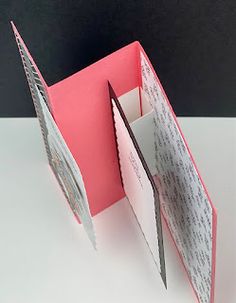 an open book with some writing on the front and back pages folded in half, sitting on a white surface