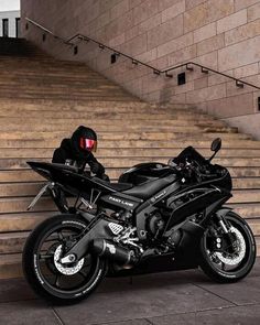 a black motorcycle parked in front of some steps and railings with a helmet on