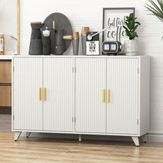 a white cabinet sitting in the middle of a room next to a potted plant