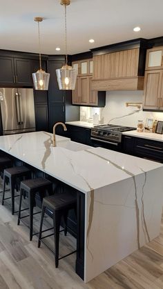 a kitchen with black cabinets and white countertops, an island in the middle is surrounded by stools