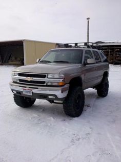 a silver truck parked in the snow near a building