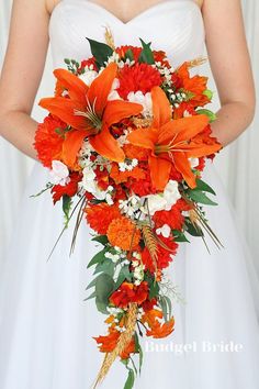 a bride holding a bouquet of orange and white flowers