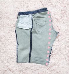 a pair of grey shorts with pink polka dots on the side, laying on a white carpet