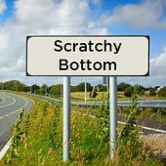 there is a sign that says scratchy bottom on the side of the road in front of an empty highway