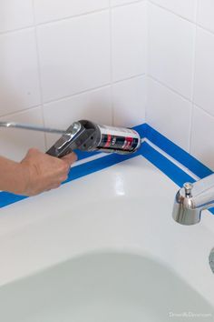 a person using a power drill to fix a sink faucet in a bathroom