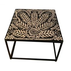 a black and white coffee table with an intricate design on the top, sitting against a white background