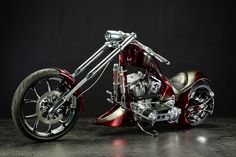 a red and silver motorcycle parked on top of a cement floor next to a black wall