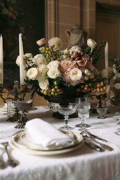 a table set with plates, silverware and flowers in a bowl on top of it