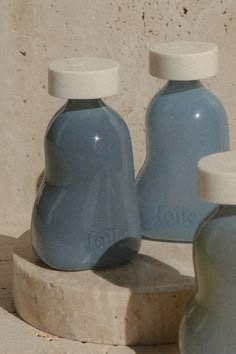 two blue vases sitting next to each other on top of a stone slab in front of a wall