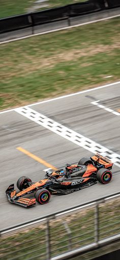 an orange race car driving down the track