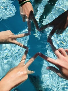 several people reaching out their hands to touch the water's surface in a pool