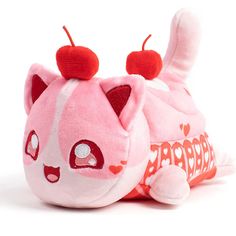 a pink cat stuffed animal laying on top of a white floor next to a red pillow