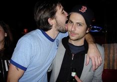 two men are kissing each other while drinking beer