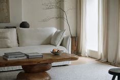 a living room with a white couch and coffee table in front of a window filled with curtains