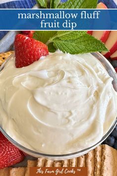 a bowl filled with fruit dip next to crackers and strawberries on a plate