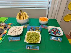 a table topped with plates and bowls filled with food next to bananas, cereals and other snacks