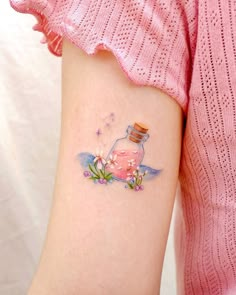 a woman's arm with a bottle and flowers tattoo on the left side of her arm