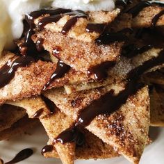 a white plate topped with waffles covered in chocolate sauce and whipped cream on top