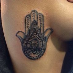 a hamsa tattoo on the back of a woman's shoulder with an eye