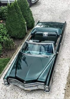 an old car is parked on the side of the road in front of some bushes